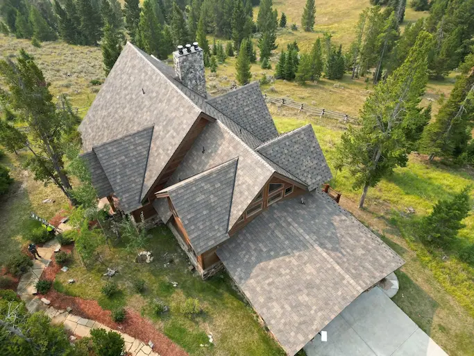 Aerial view of multi-gable asphalt shingle roof replacement on a Montana cabin near Bozeman, MT