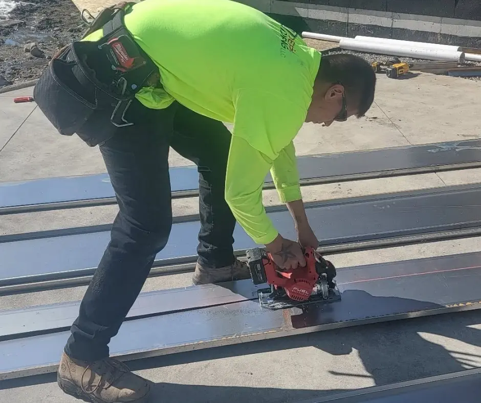 Roofer repairing damaged metal roof after storm damage on a Bozeman, MT home